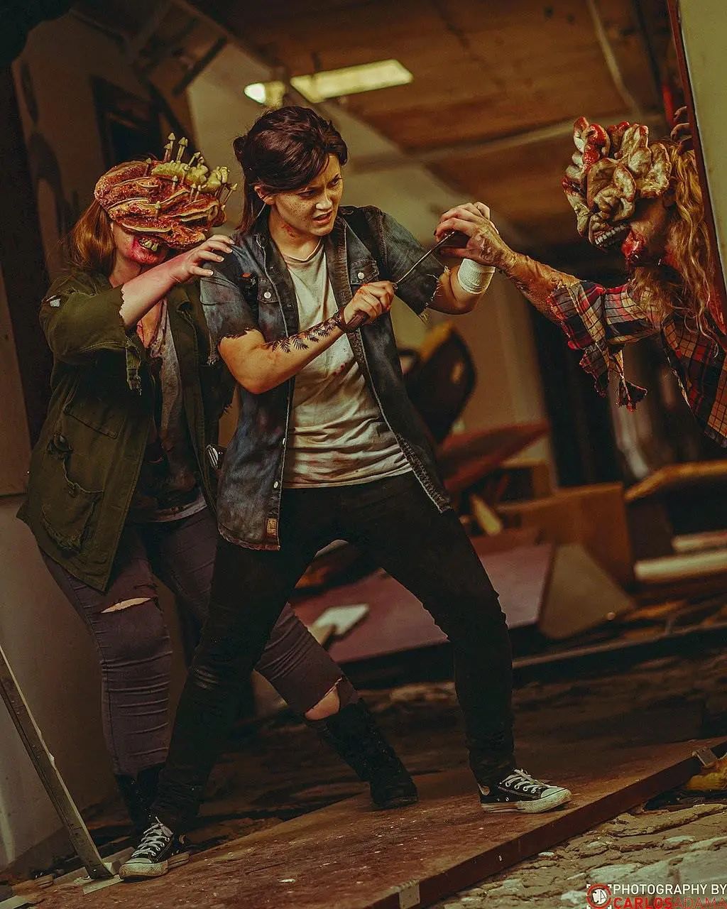 Cosplayer de Ellie enfrentando dois Clikers e reproduzindo uma cena de The Last of Us Part II.