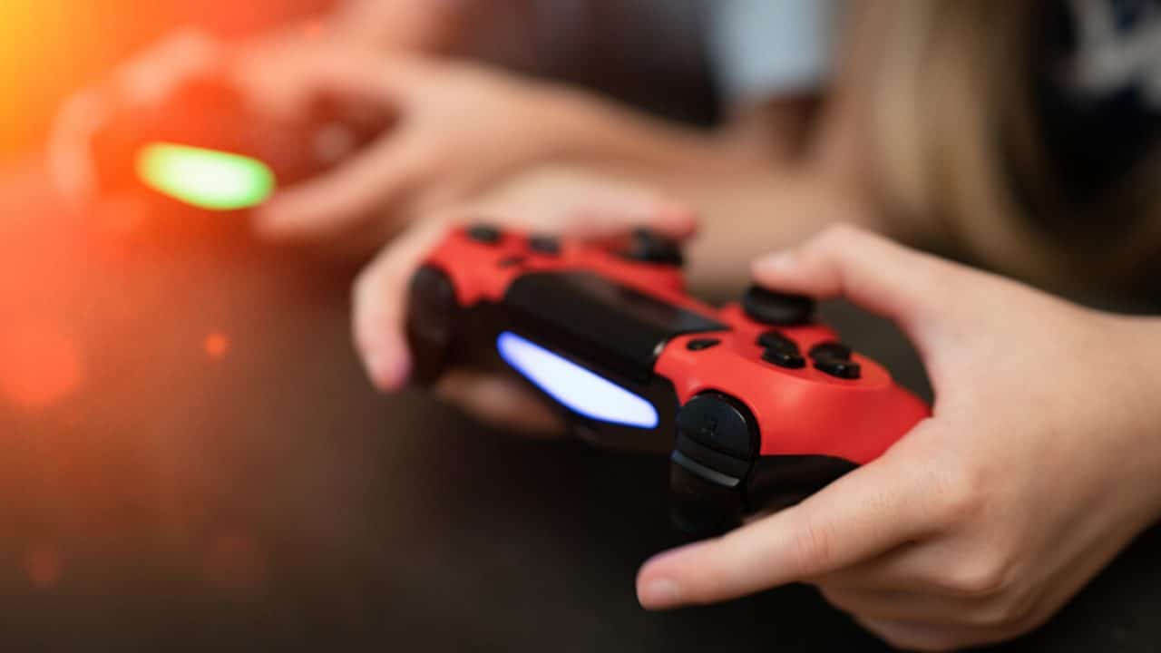 Imagem mostra dois controles de PS4 segurados por duas mãos para fazer alusão à indústria de games