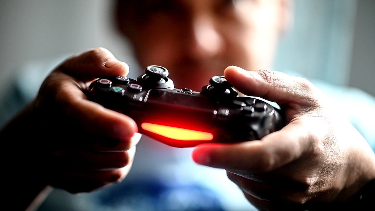 Pessoa que um controle de vídeogame nas mãos, provavelmente um consumidor do mercado de games.