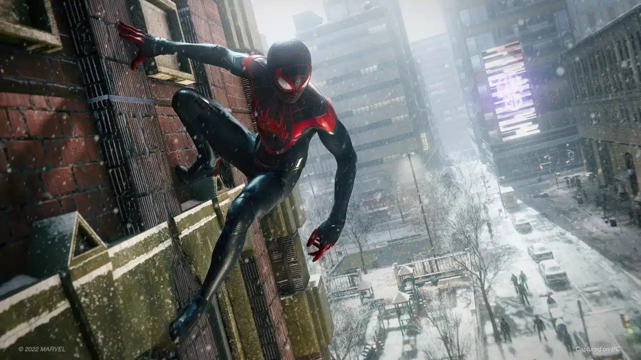 imagem de Spider-Man Miles Morales com um homem de roupa preta e vermelha segurando em um predio e olhando para a neve na rua