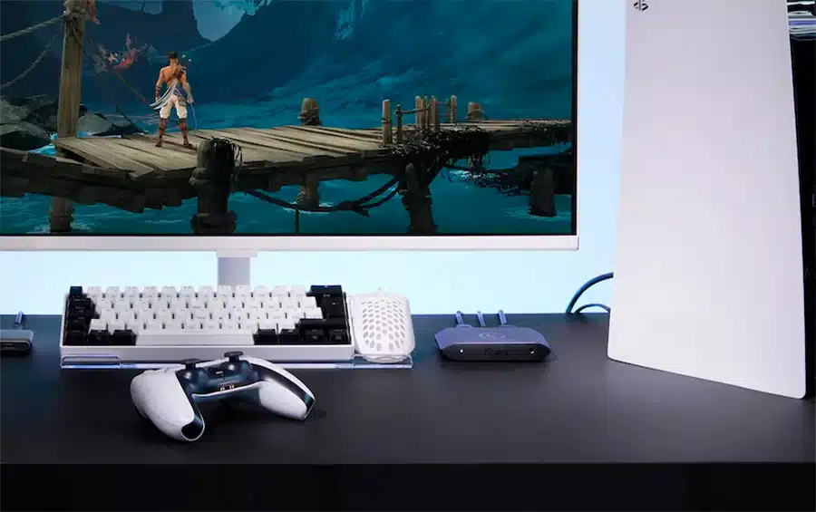 Foto de uma Elgato 4K X sobre a mesa, fazendo capturas de um PS5 ao lado de um monitor e teclado.