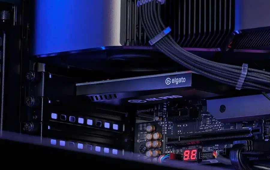 Foto de uma Elgato 4K Pro conectada à placa-mãe de um PC, embaixo de uma placa de vídeo.