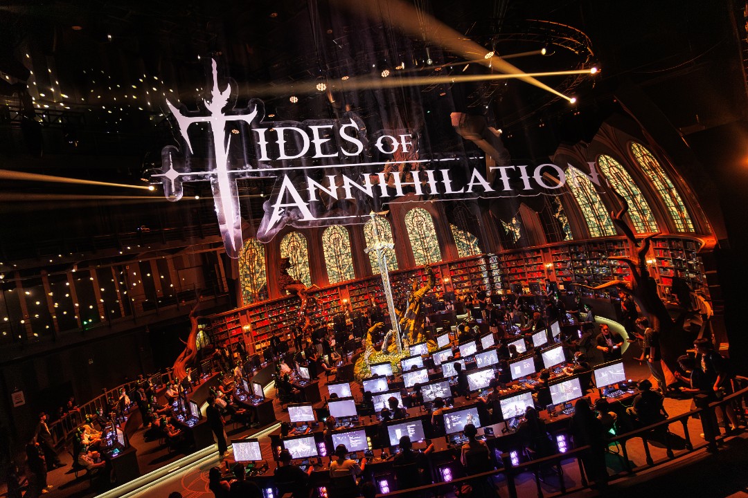 Evento de Tides of Annihilation com diversas estações de jogo, decoração inspirada no universo do game e o logotipo projetado sobre o cenário.
